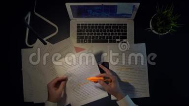一个男人拿着笔记本电脑坐在桌子旁，在文件中标记单词。
